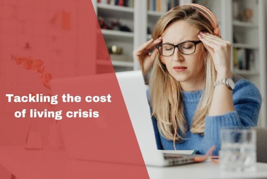 Woman looking exasperated sat at laptop, with blog title 'tackling the cost of living crisis' overlay