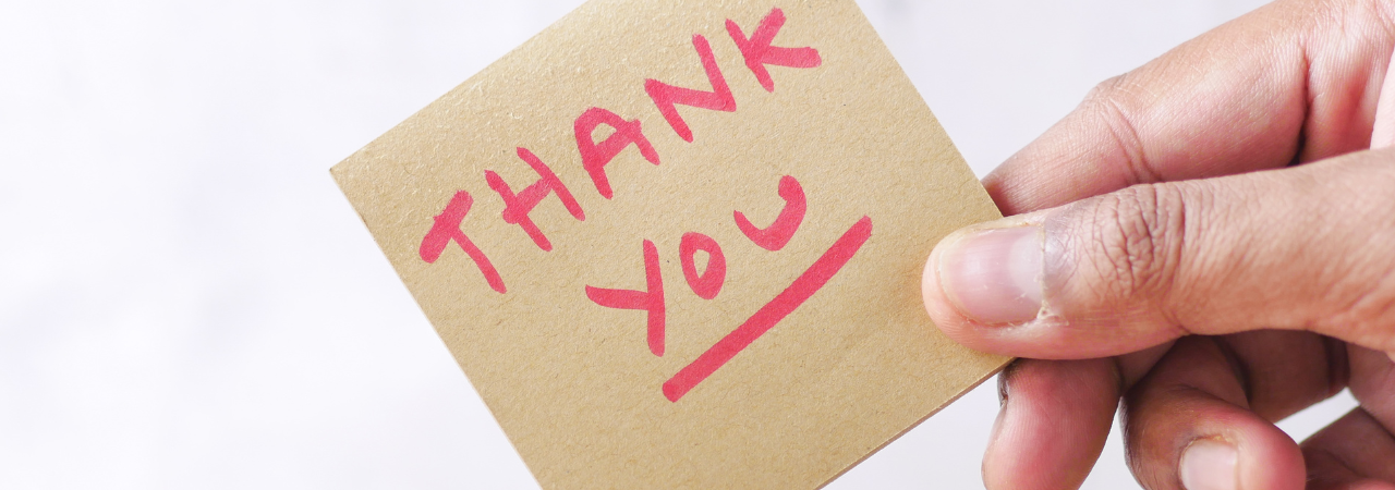 an image of a hand holding a post it note saying "Thank you" for employee appreciation day