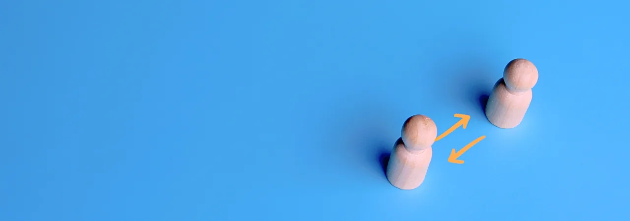two wooden playing pieces next to eachother, against blue background